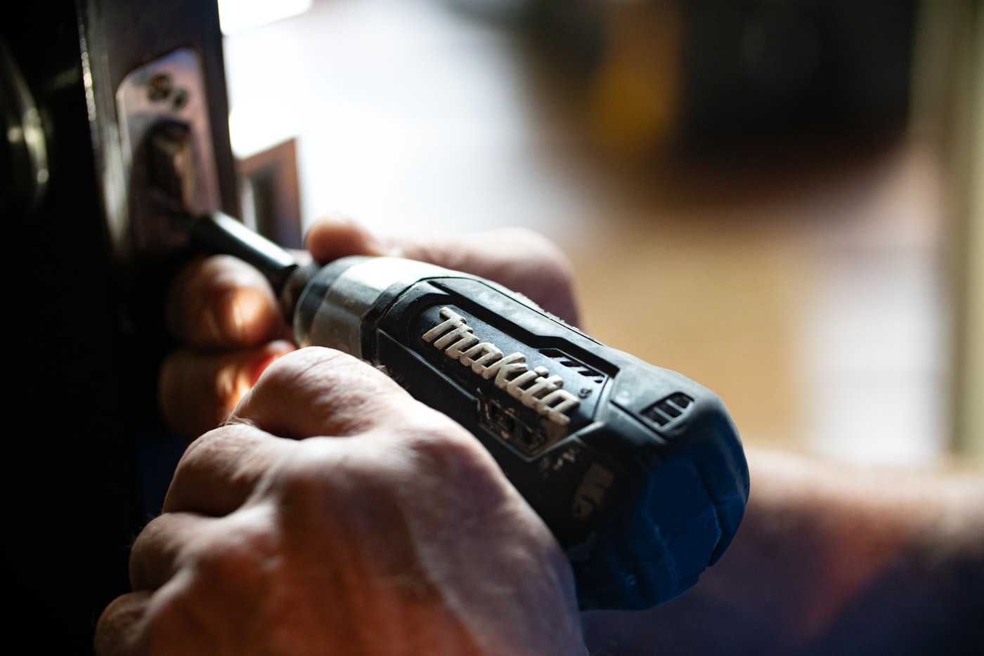 Locksmith repairing door lock hardware with a power tool